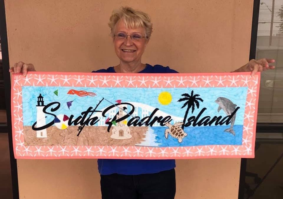 A woman is holding a sign that says south padre island