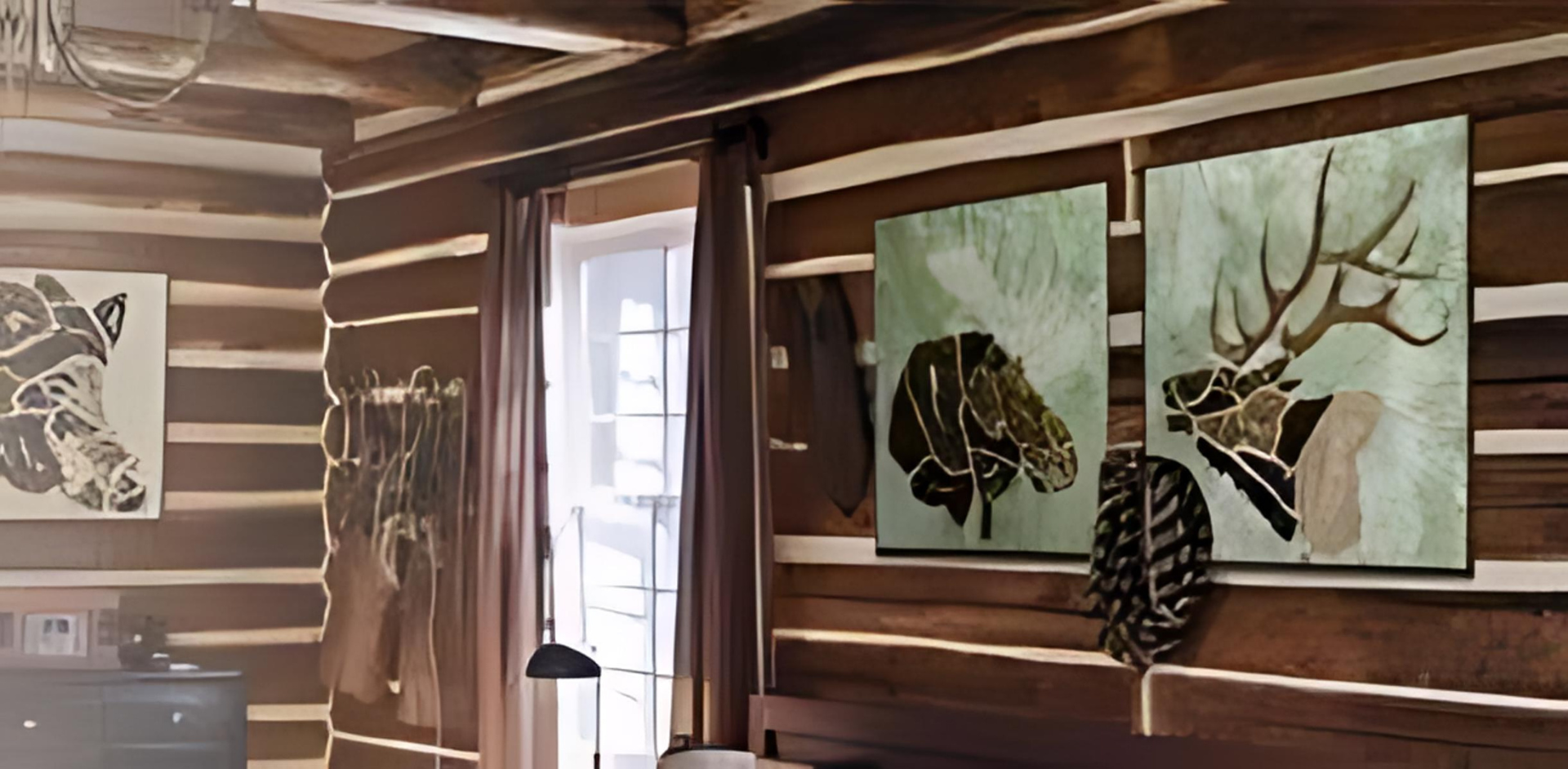 A bedroom in a log cabin with three paintings on the wall