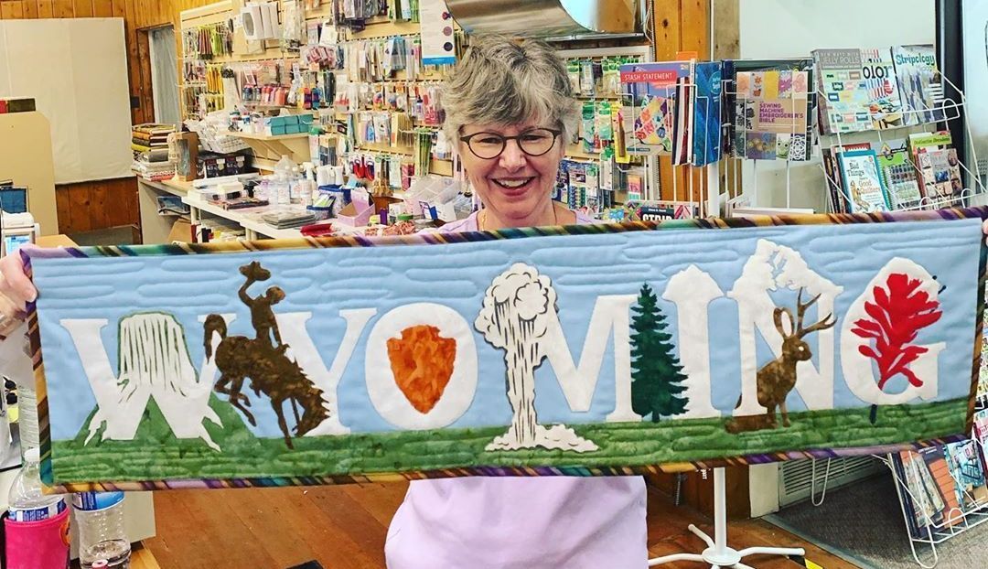 A woman is holding a quilt with the word montana on it.