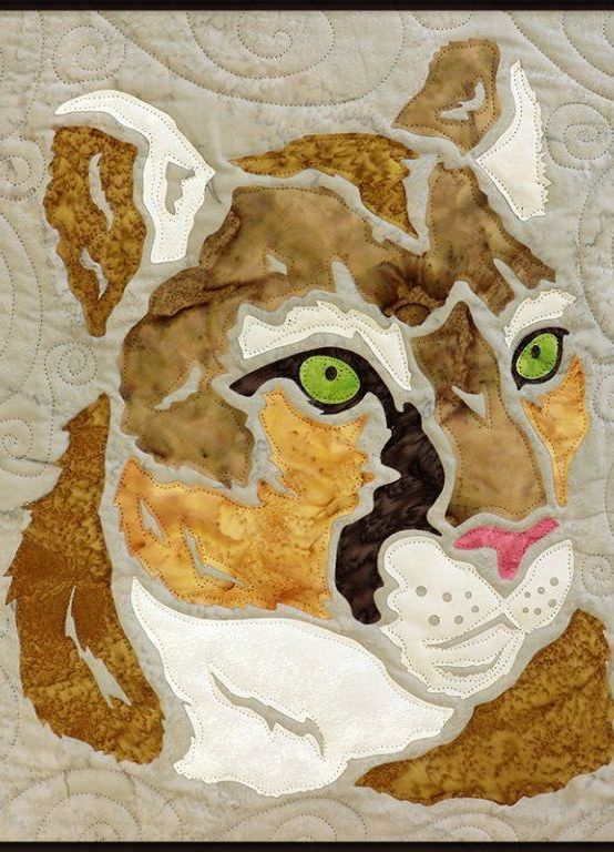 A quilt of a tiger 's head with green eyes