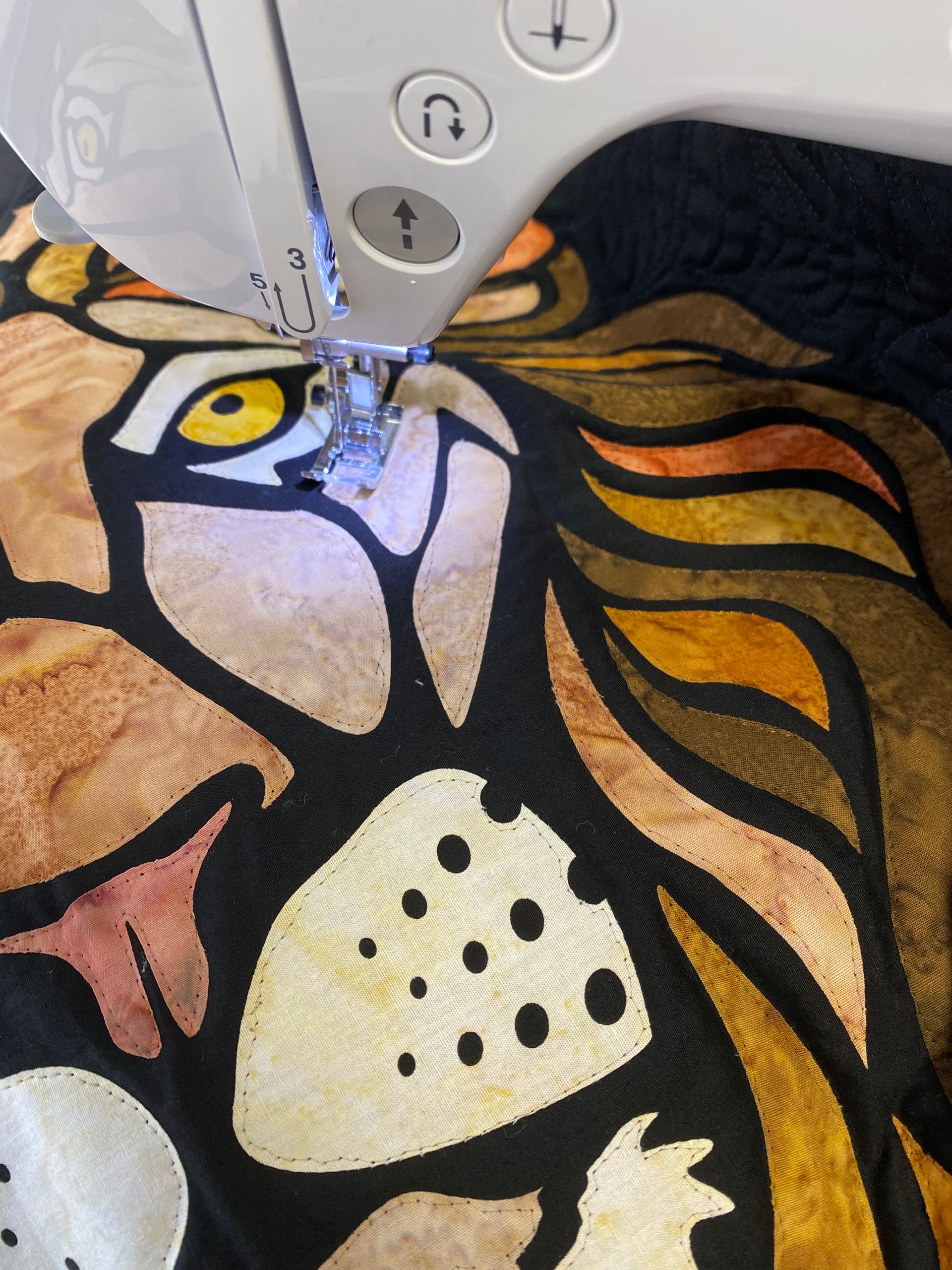 A sewing machine is stitching a picture of a lion