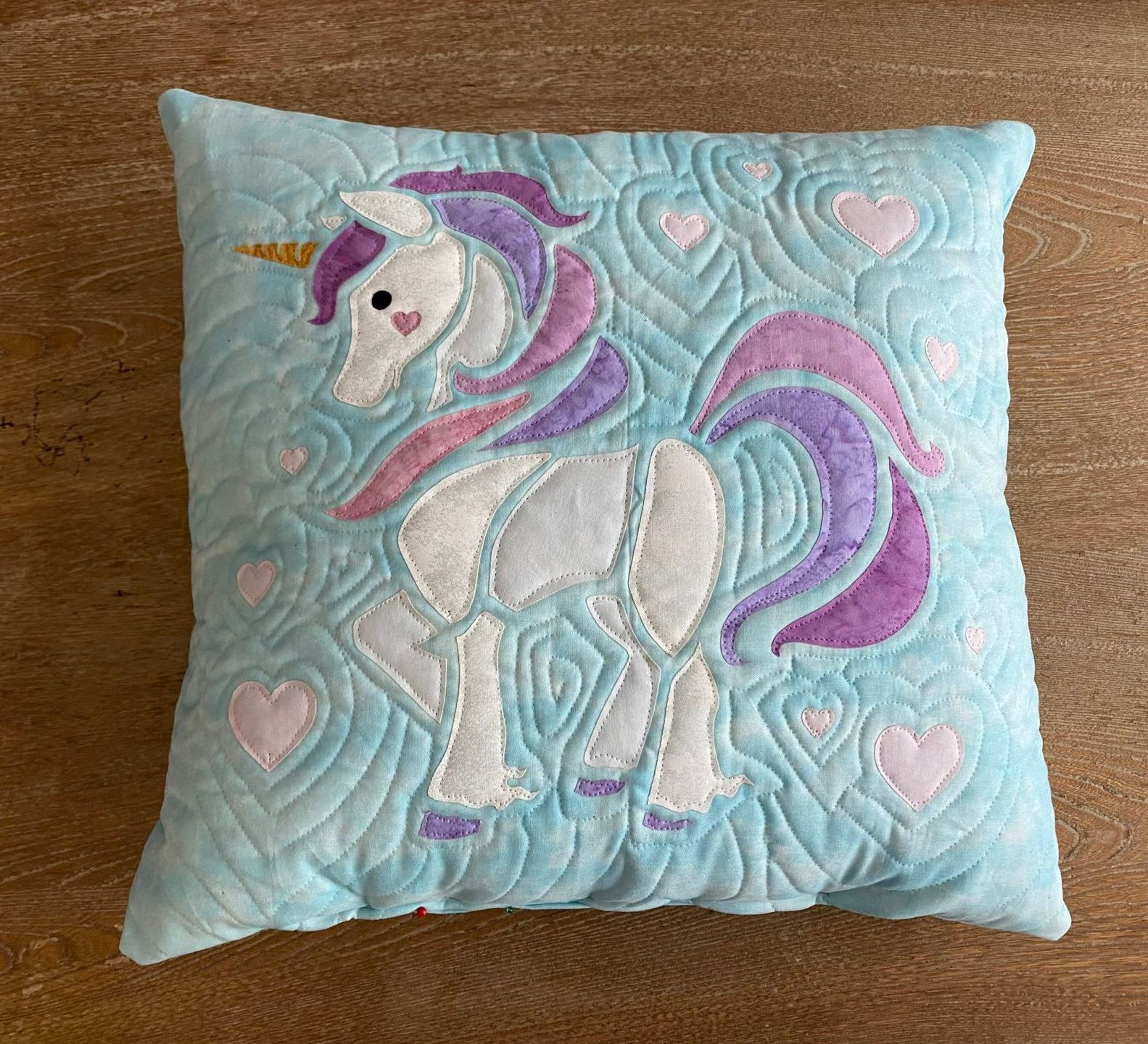 A blue pillow with a unicorn embroidered on it