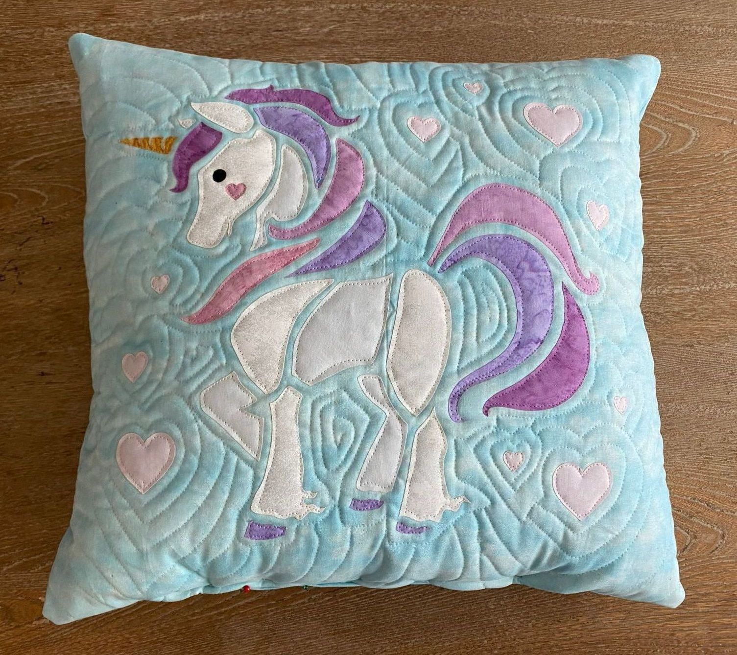 A blue pillow with a unicorn embroidered on it