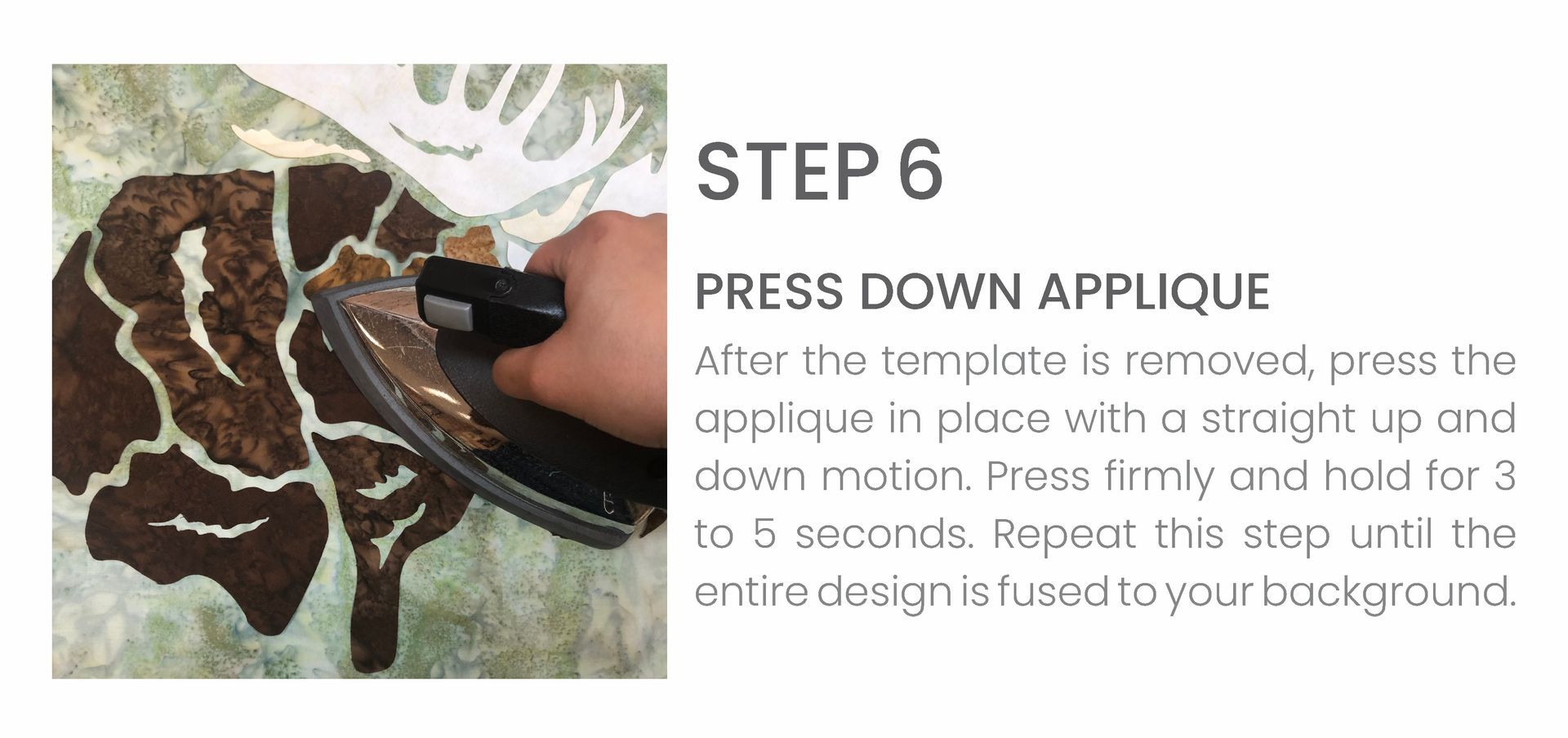 A person is using an iron to press down applique on a piece of fabric.