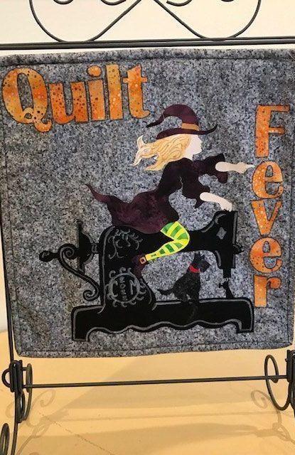 A quilt with a witch on a sewing machine