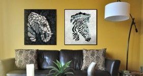 A living room with a couch , lamp , and two paintings on the wall.