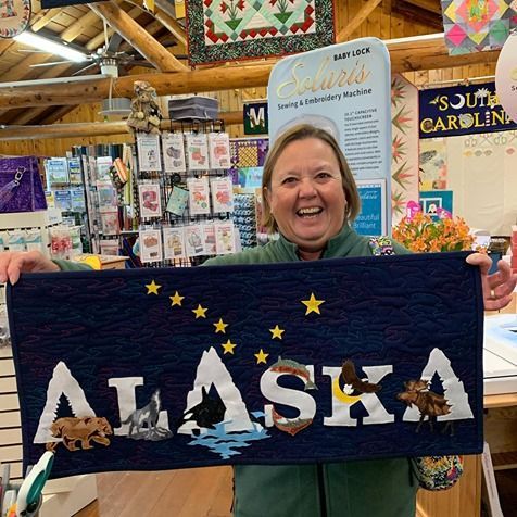 A woman is holding a sign that says alaska in a store.