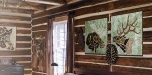 A bedroom in a log cabin with three paintings on the wall.