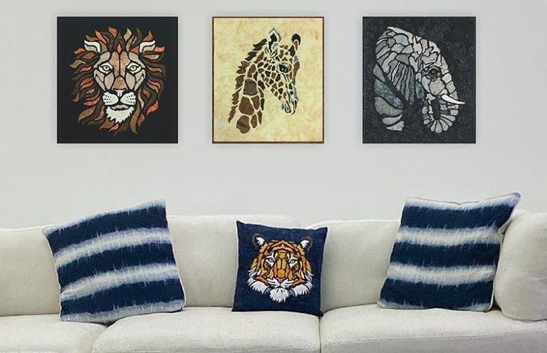 A living room with a couch and three paintings of animals on the wall.