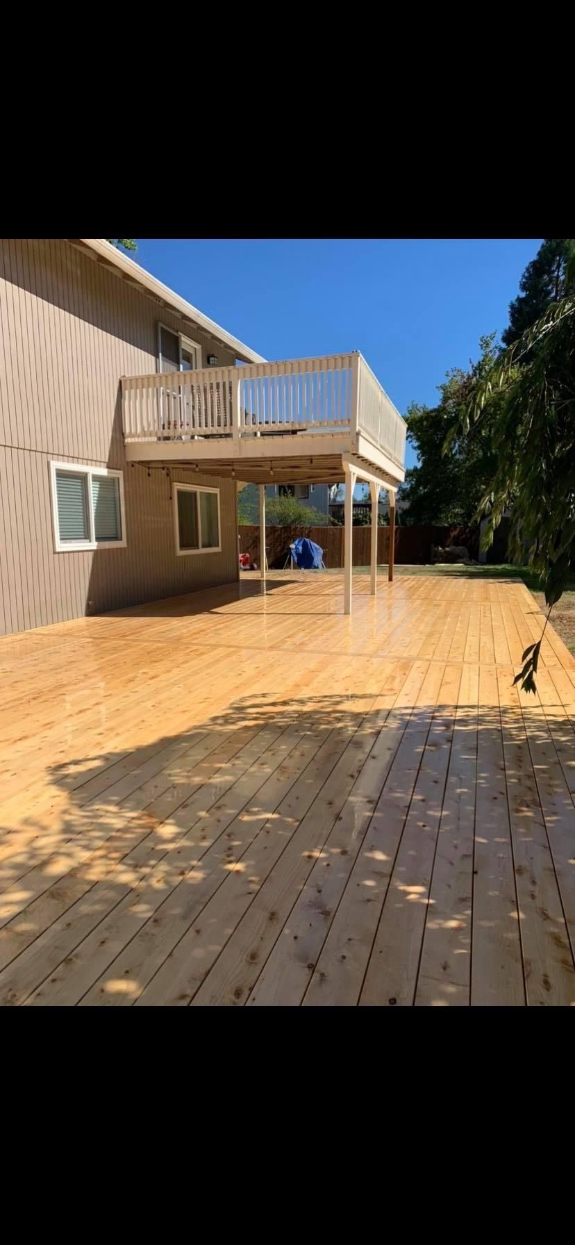 A large wooden deck is sitting in front of a house.