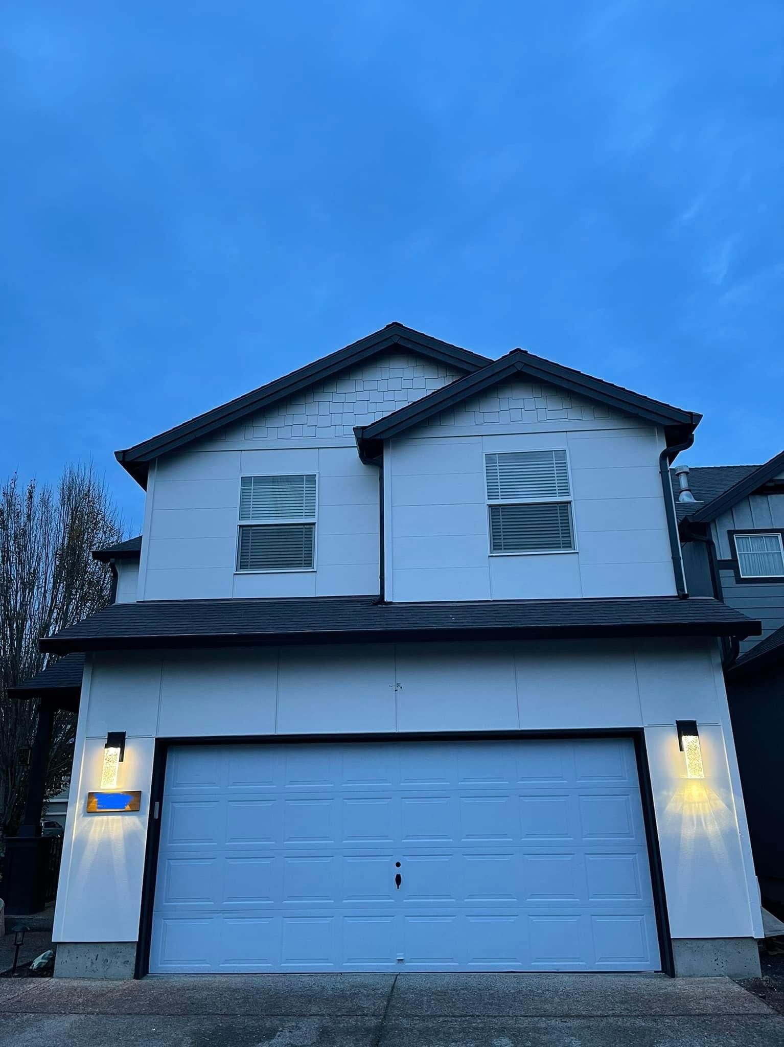 A white house with a blue garage door and a blue sky in the background.