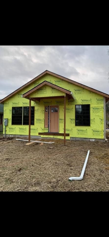A house is being built with green siding and a porch.
