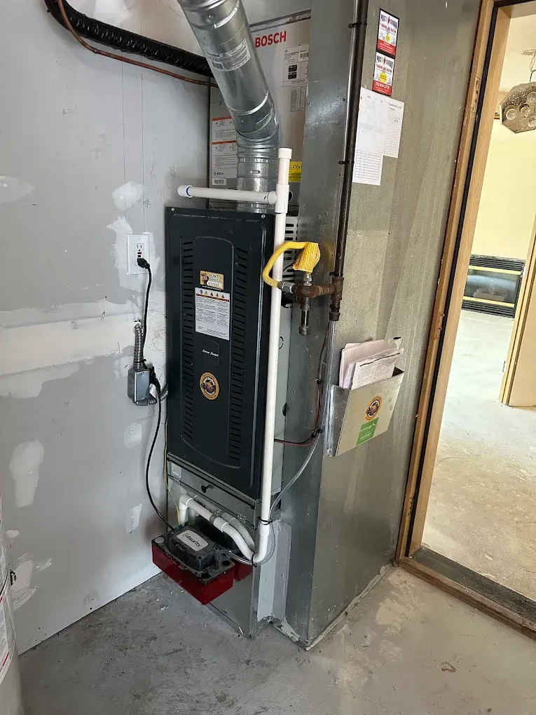 Furnace unit in a utility room with attached pipes and wiring.