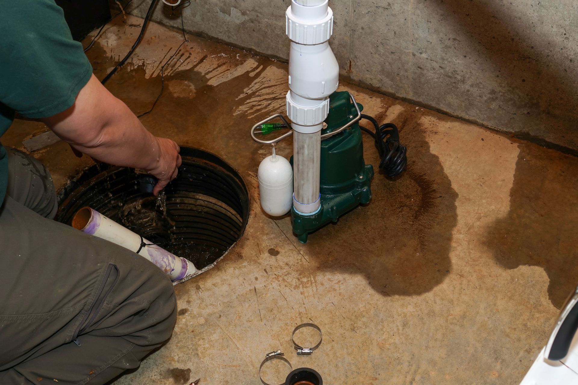 Professional plumber installing a sump pump system in a residential basement.