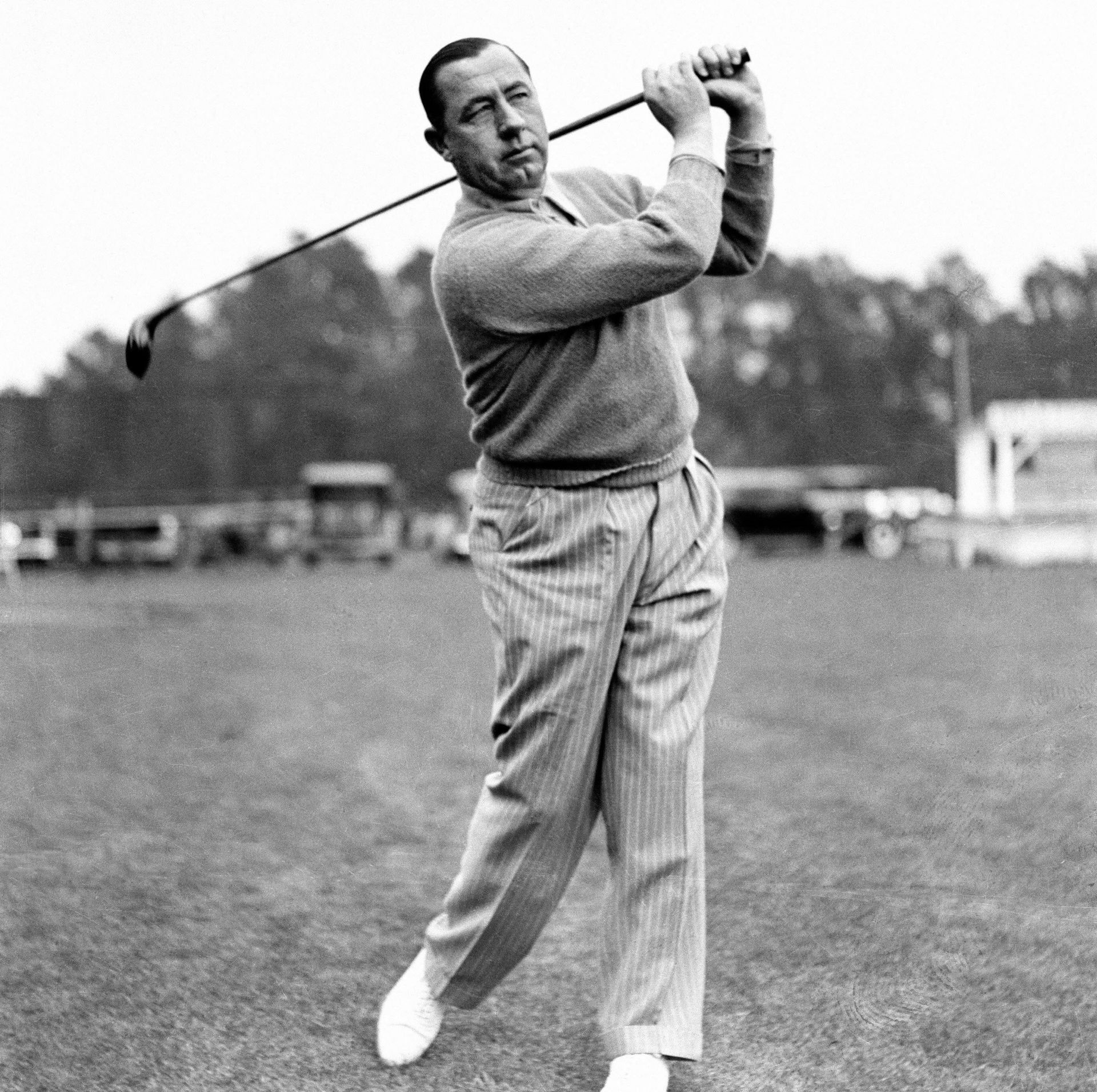 A man is swinging a golf club in a black and white photo.