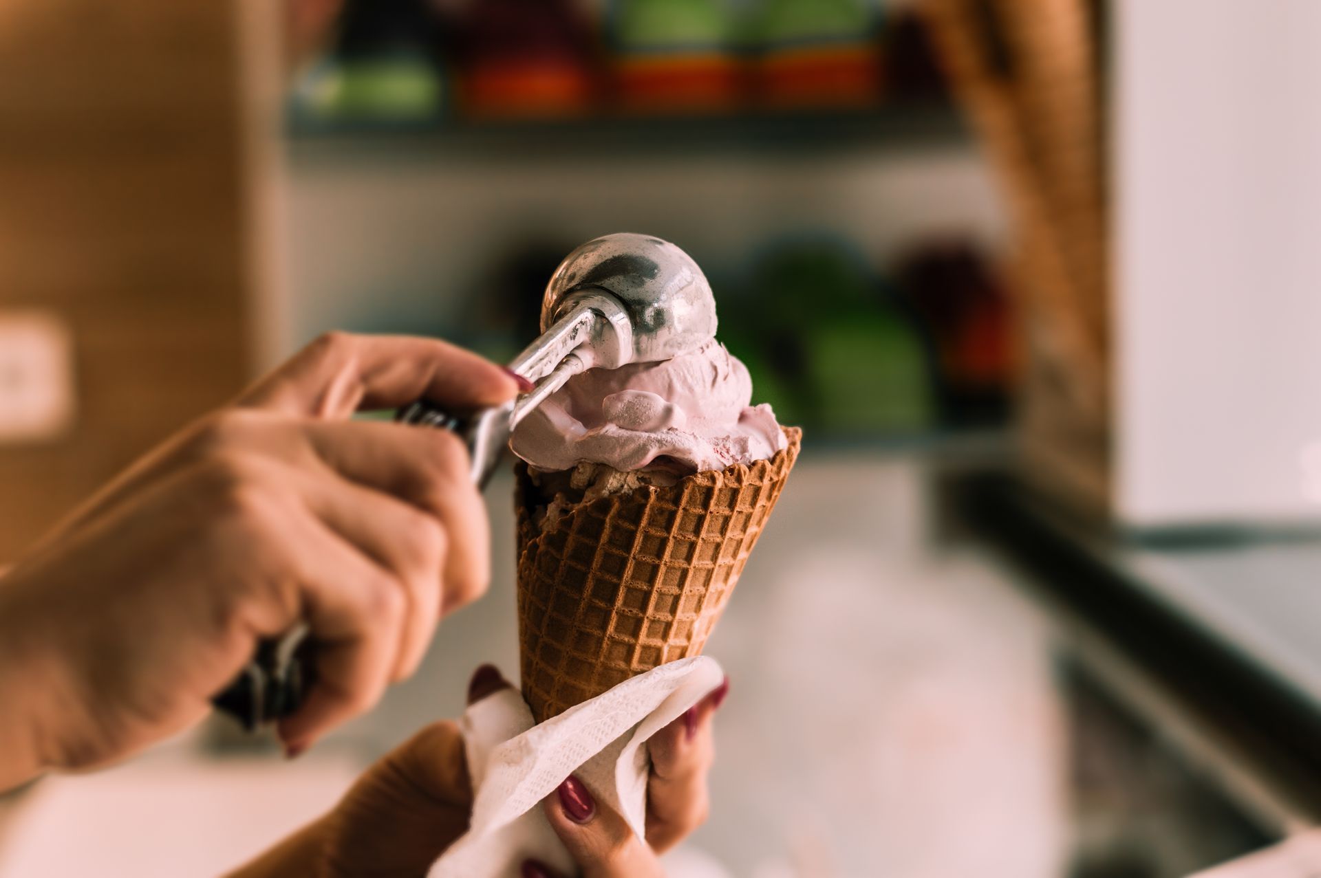 A person is scooping ice cream into an ice cream cone.