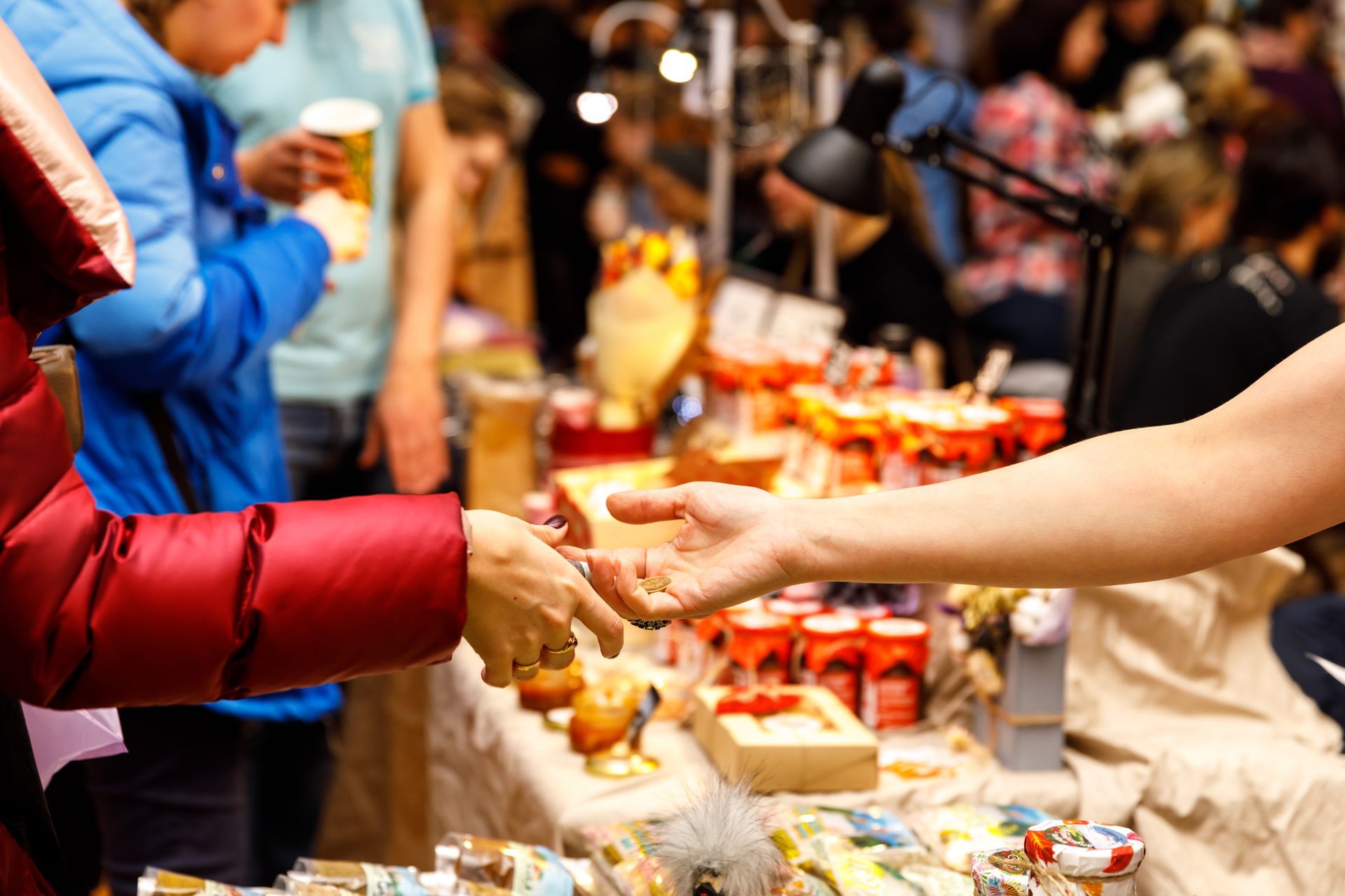 A woman is giving a gift to another woman at a market.