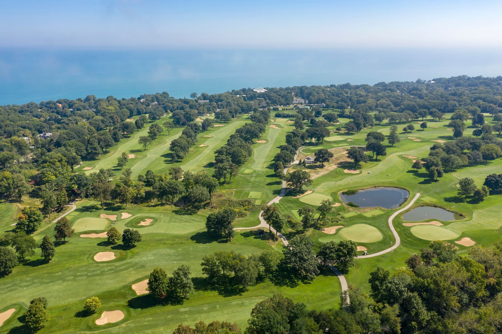 An aerial view of a golf course surrounded by trees and a body of water.