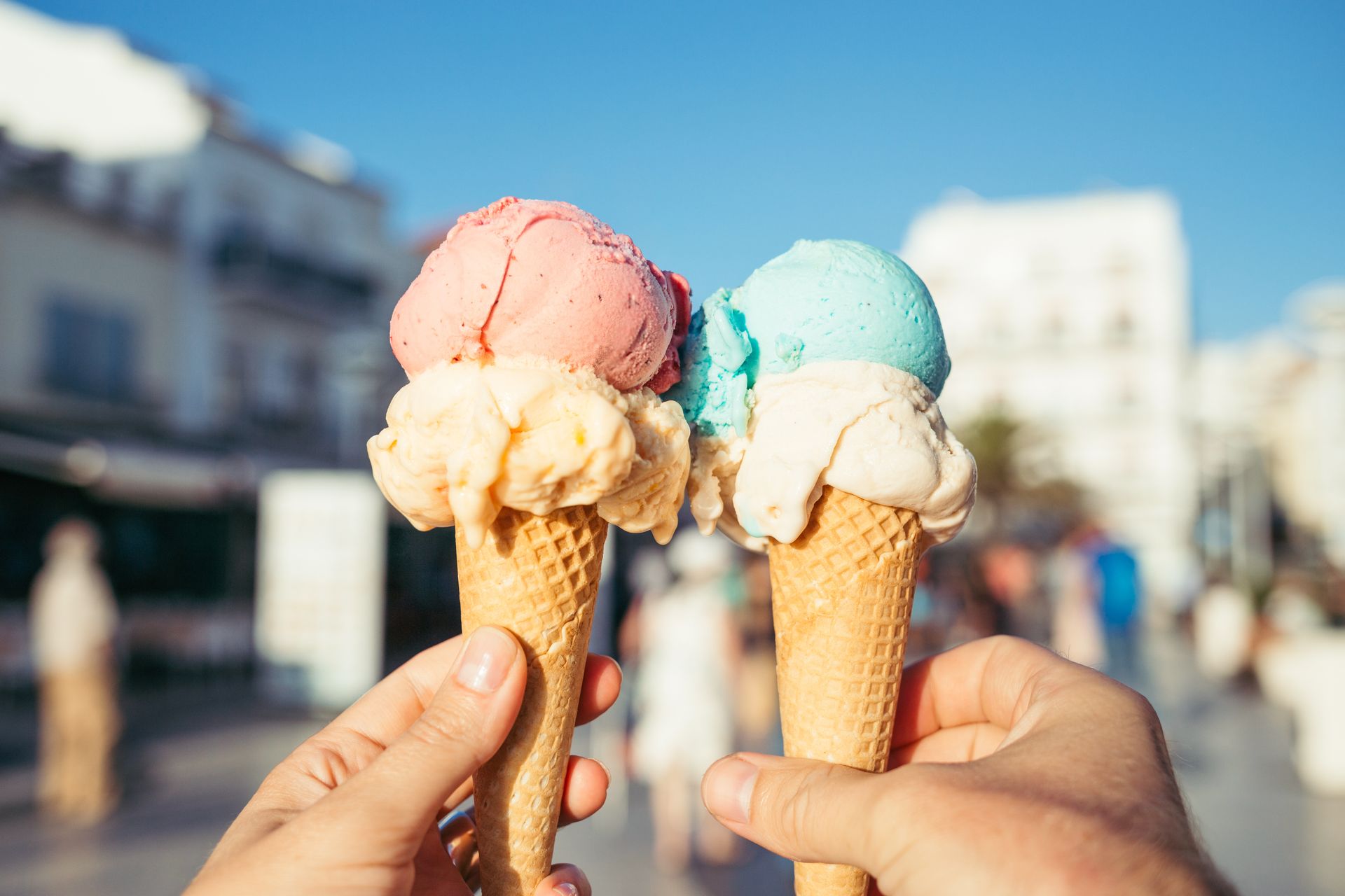 A person is holding two ice cream cones in their hands.