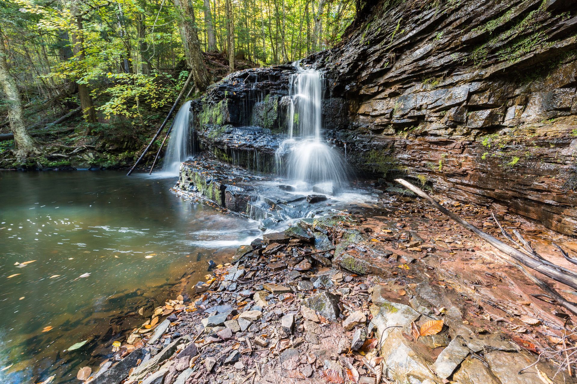 A waterfall is surrounded by rocks and trees in the middle of a forest.