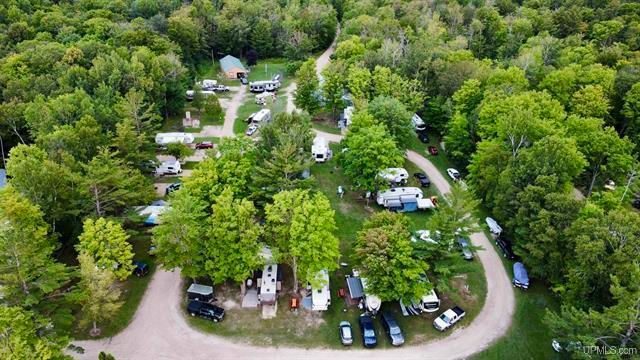 an aerial view of a campground surrounded by trees and a dirt road .