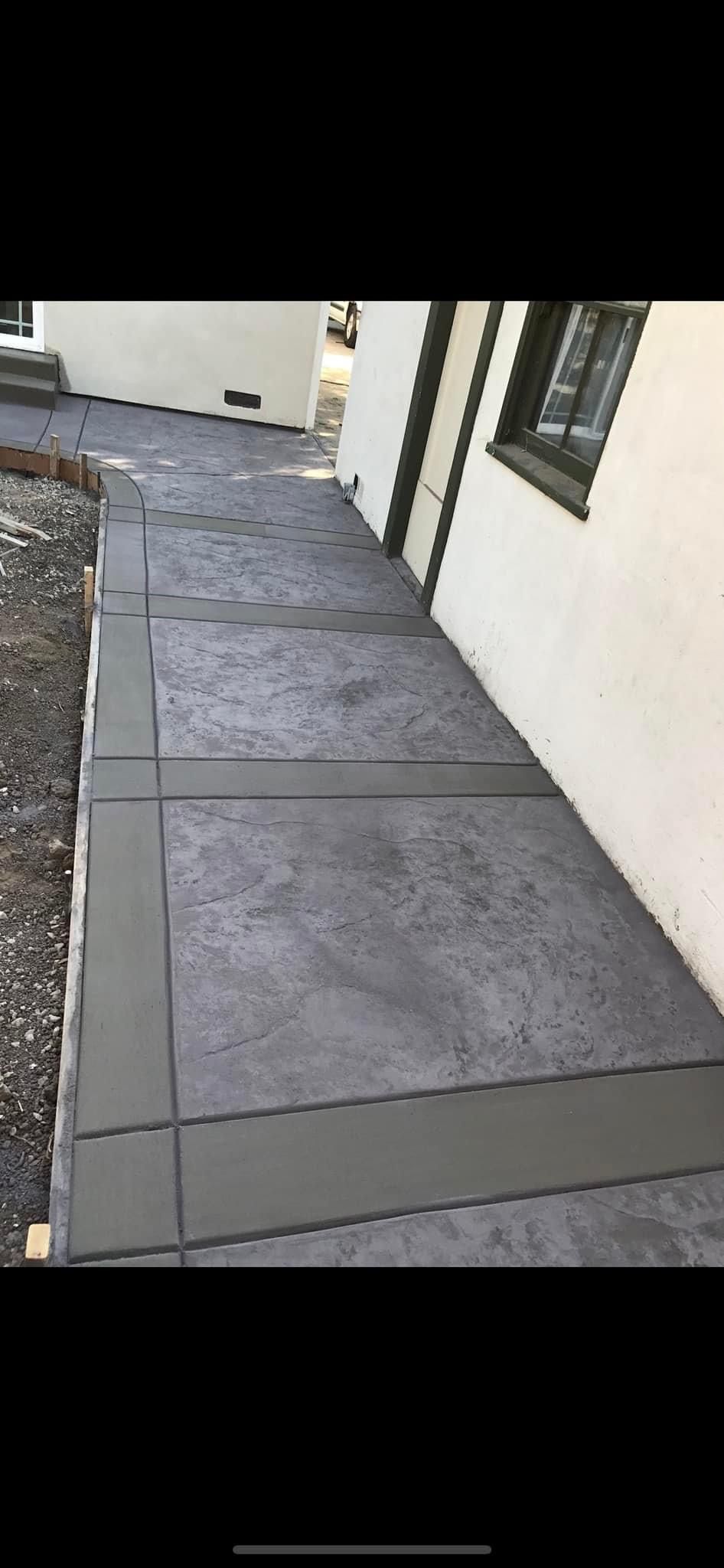 Concrete pathway with a border alongside a white building.