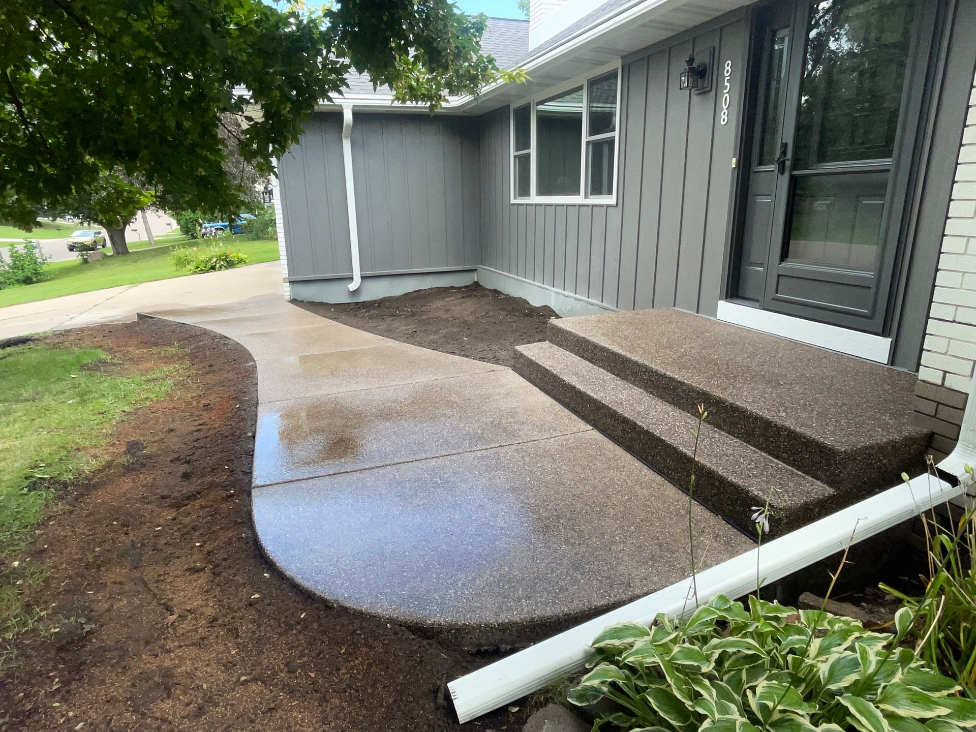 A house with a concrete patio and stairs in front of it.