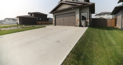A concrete driveway leading to a house with a garage.