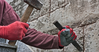 A man is holding a hammer and a chisel in his hands.