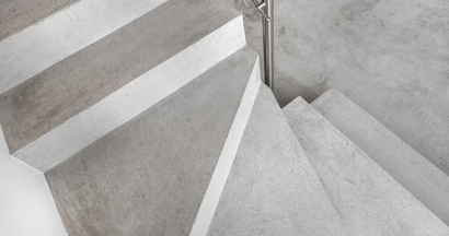 A close up of a concrete spiral staircase with a metal railing.