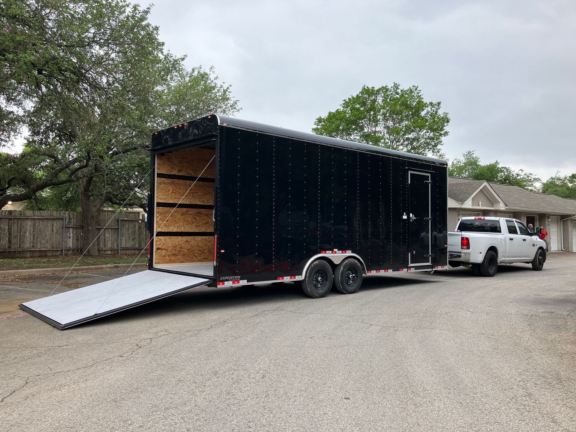 Black enclosed trailer with ramp attached to a white pickup truck