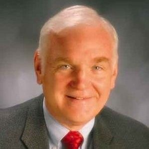 A man in a suit and tie is smiling for the camera.