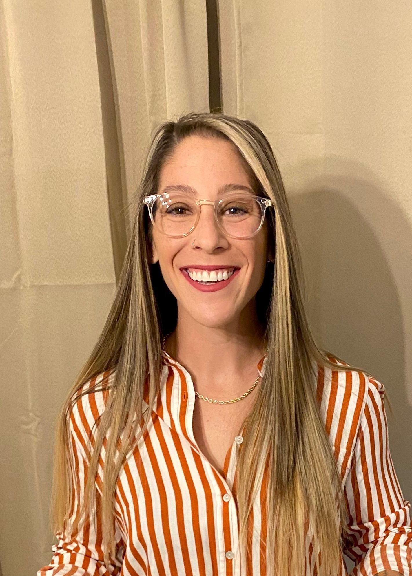 Devon wearing glasses and a striped shirt is smiling for the camera.