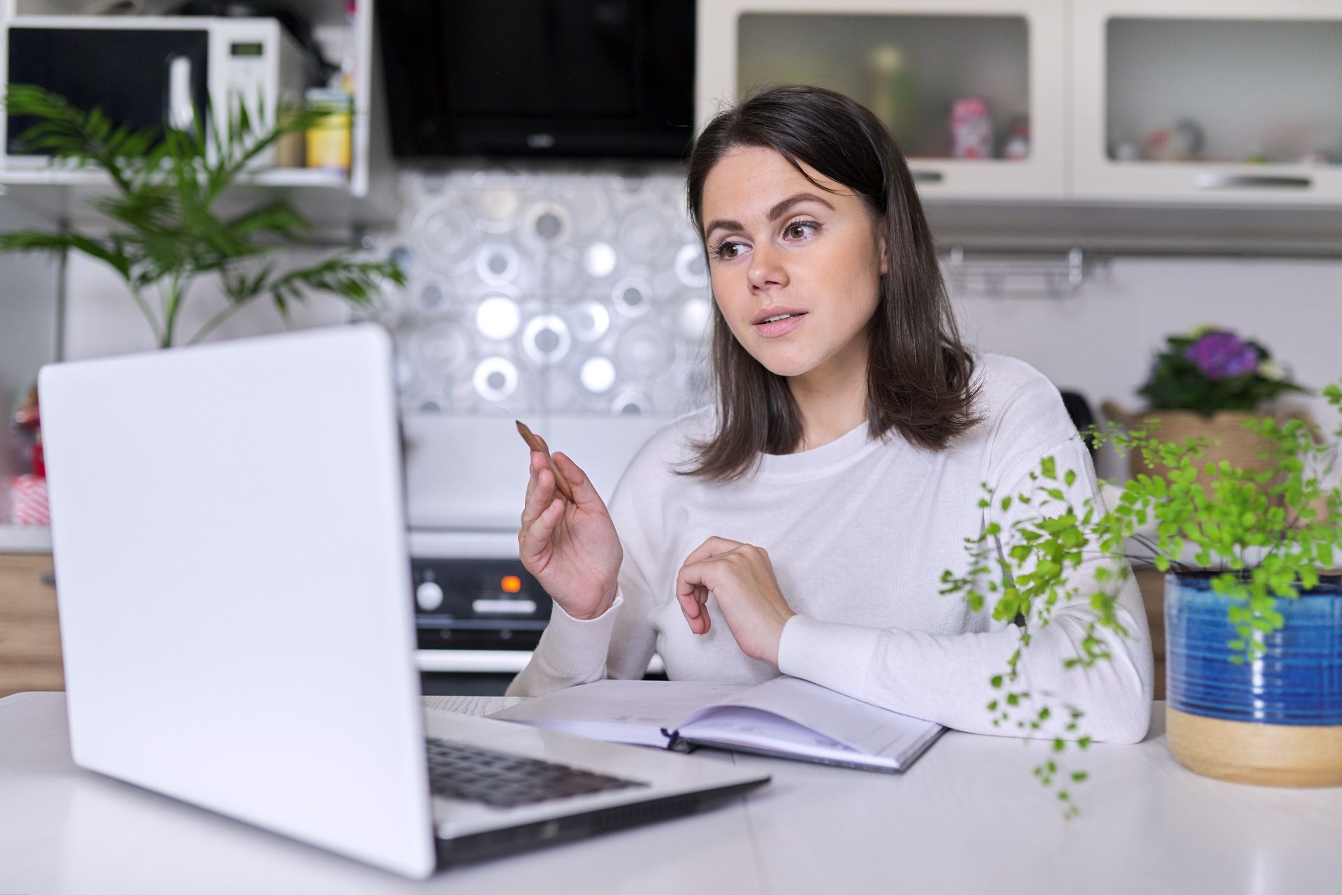 A woman is sitting at a table in front of a laptop computer.