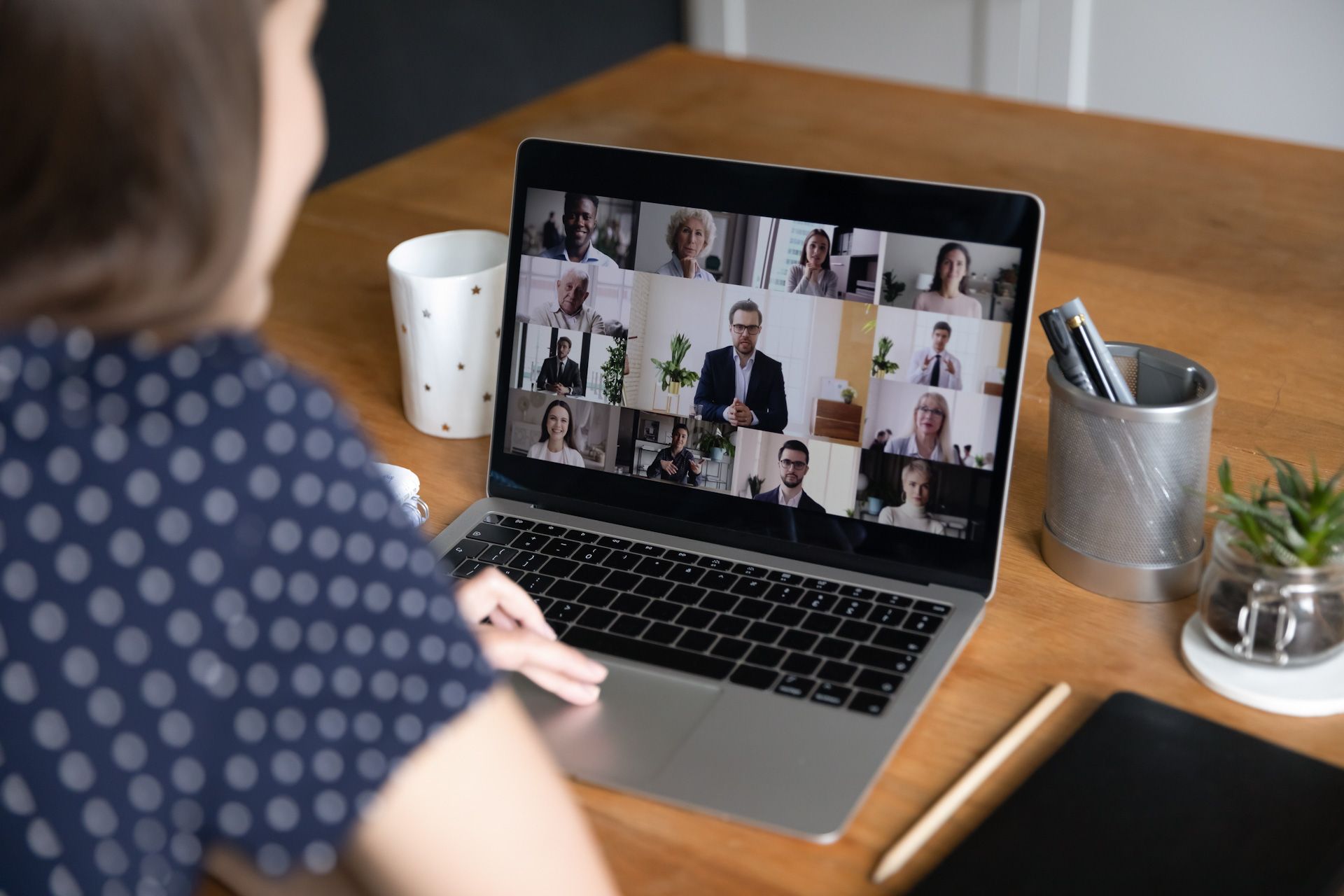 A woman is sitting at a desk using a laptop computer to have a video call.