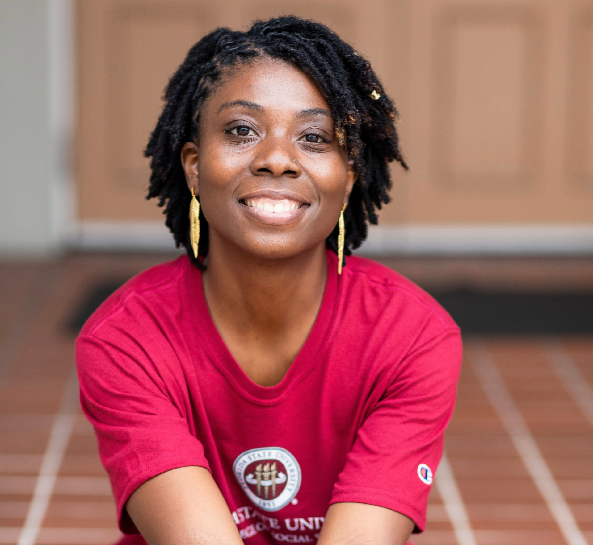 Anastasia wearing a black shirt and yellow earrings is smiling for the camera.