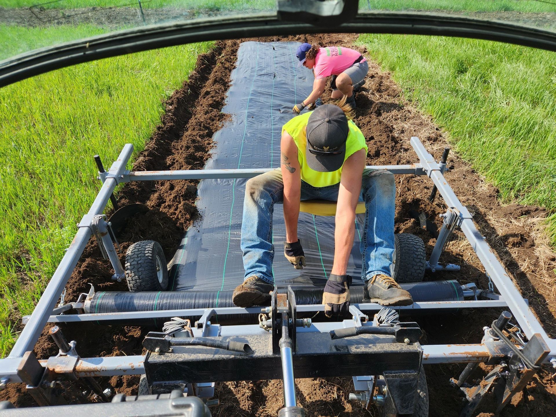 Two men are working on a machine in a field