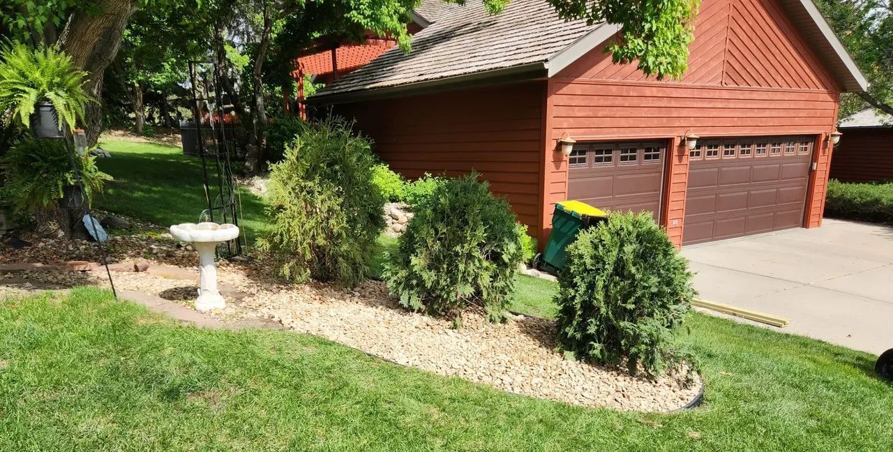 There is a bird bath in the middle of the yard in front of a garage.
