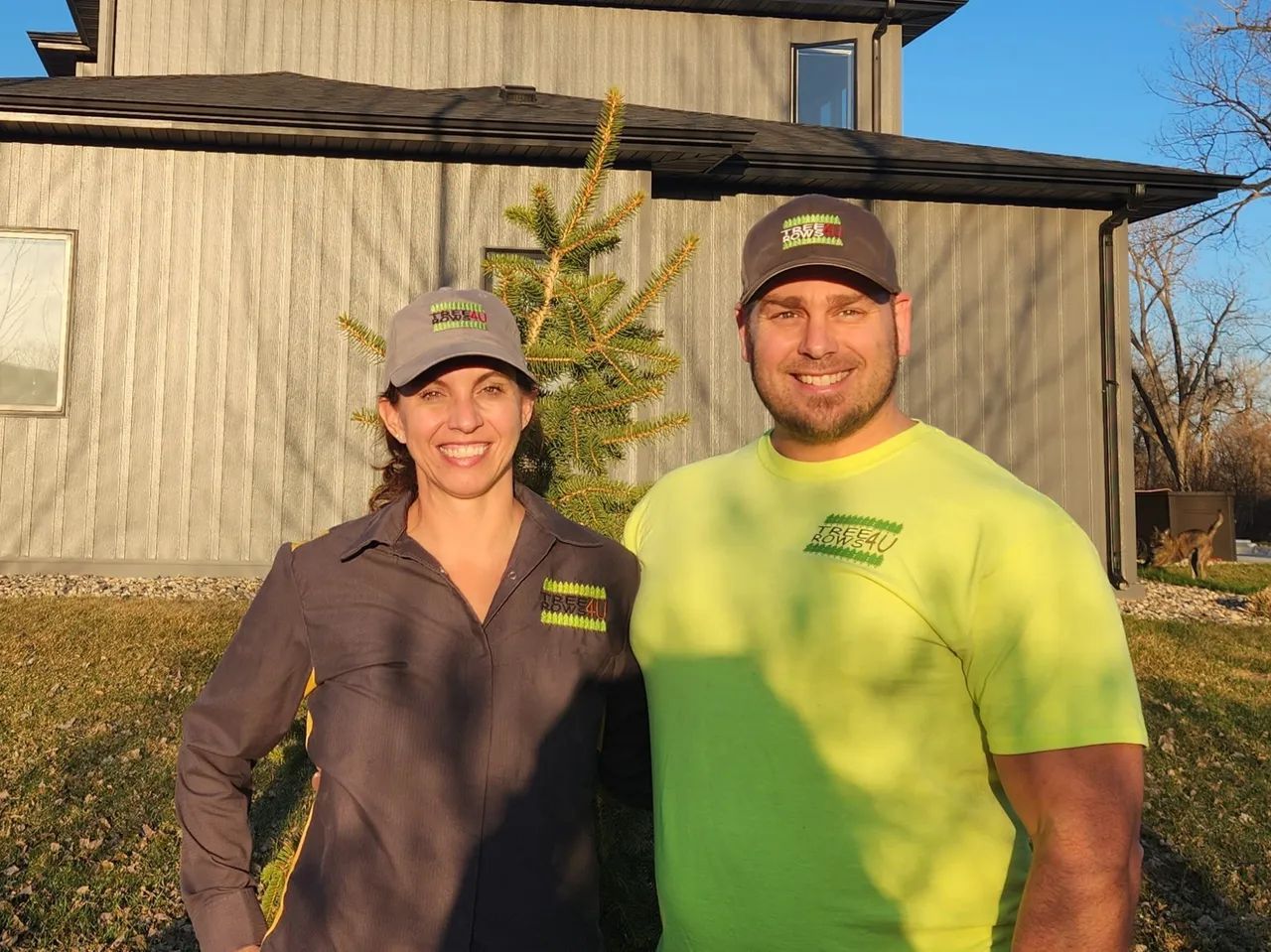 A man and a woman are posing for a picture in front of a house.