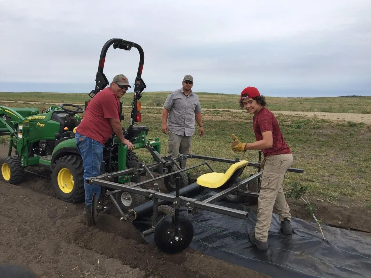 A group of people are working on a tractor in a field.