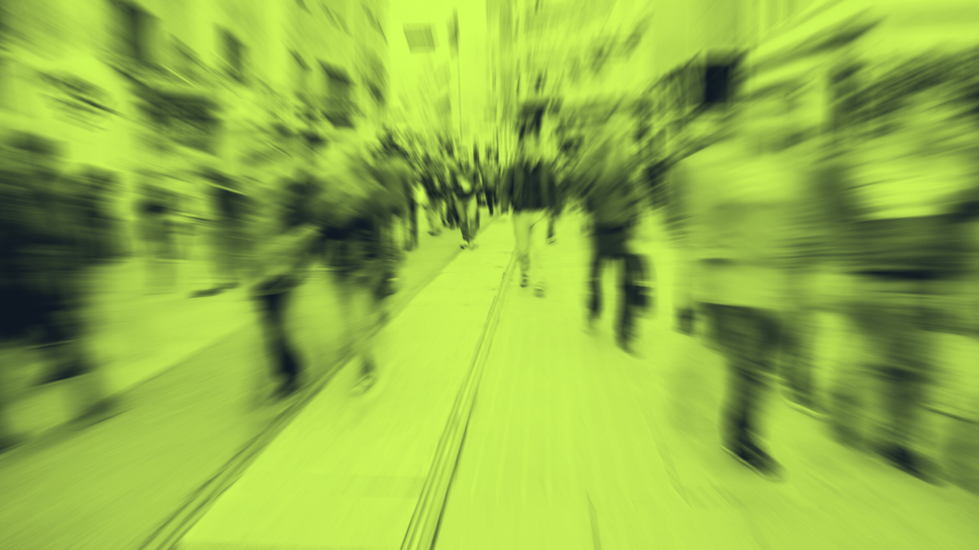 A blurred, green-tinted view of people walking along a pedestrian street.