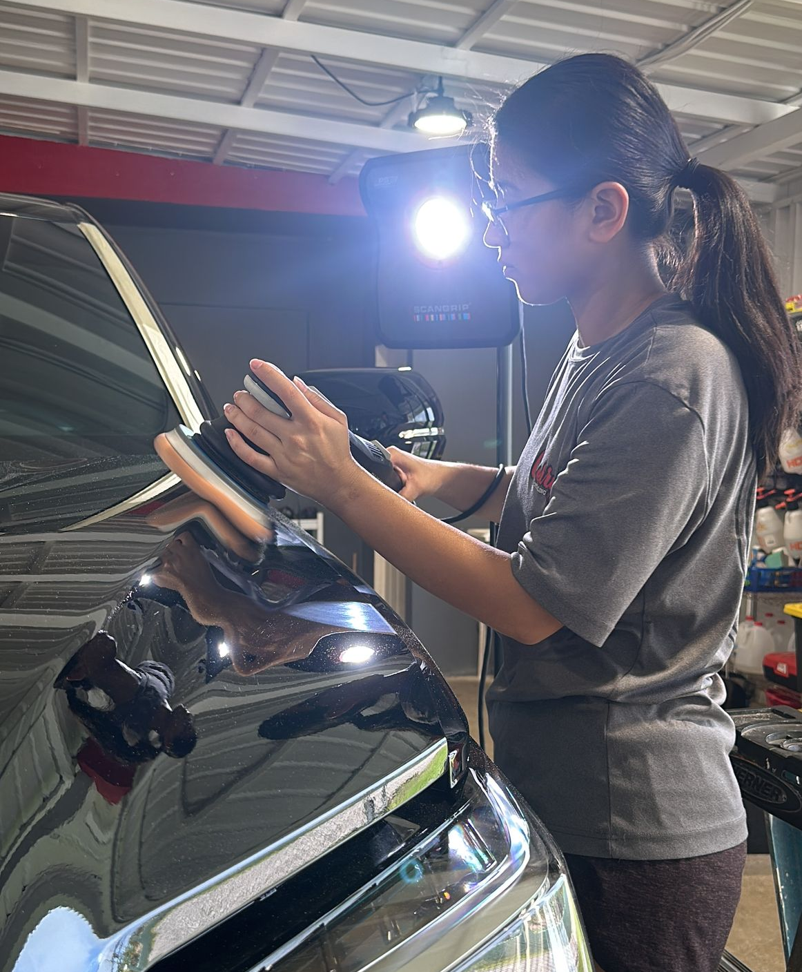 A man is cleaning a white car in a garage.