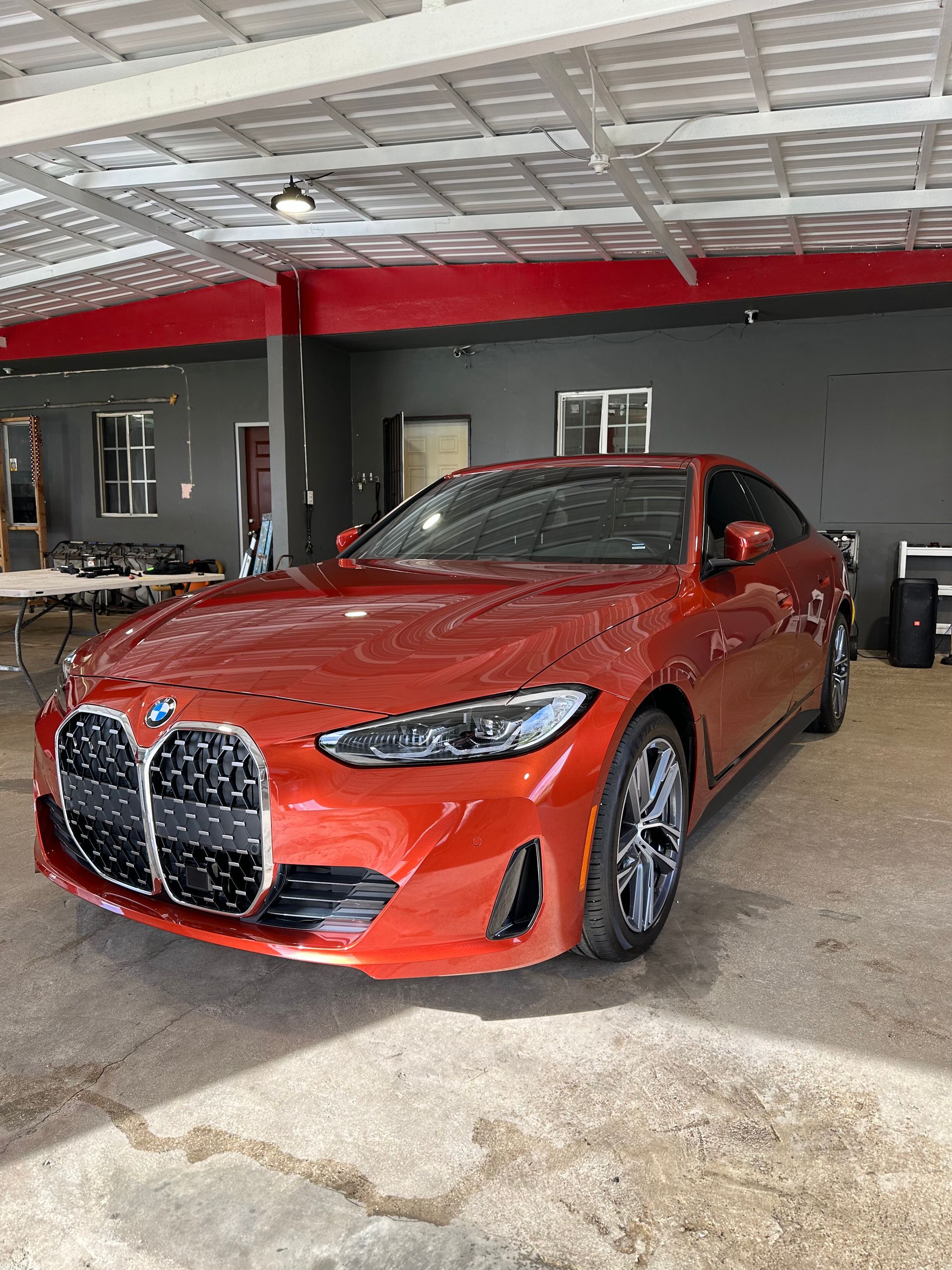 A red bmw 4 series coupe is parked in a garage.