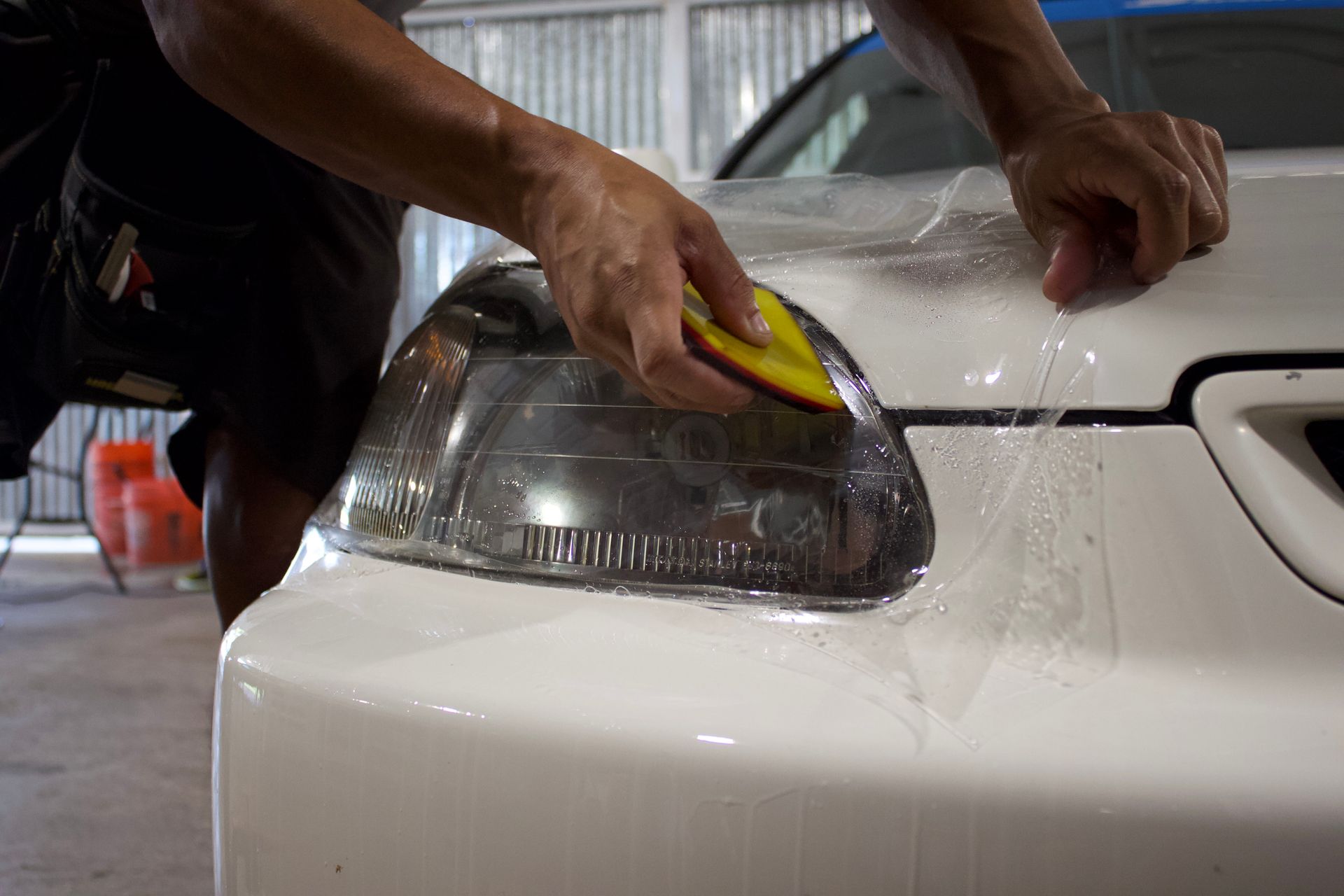A man is standing next to a white car in a garage.