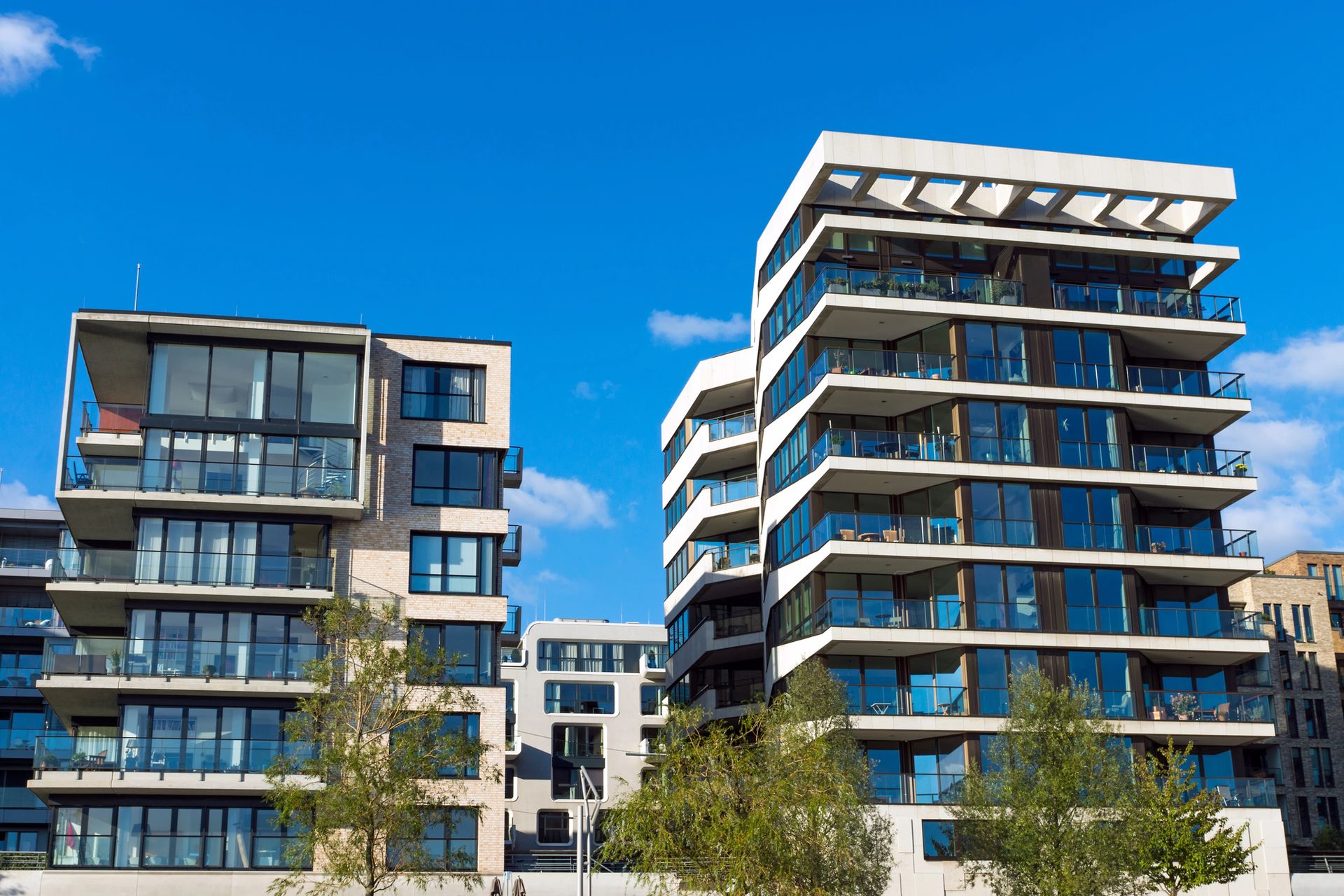 Modernos edificios de apartamentos con balcones de cristal bajo un cielo azul brillante.