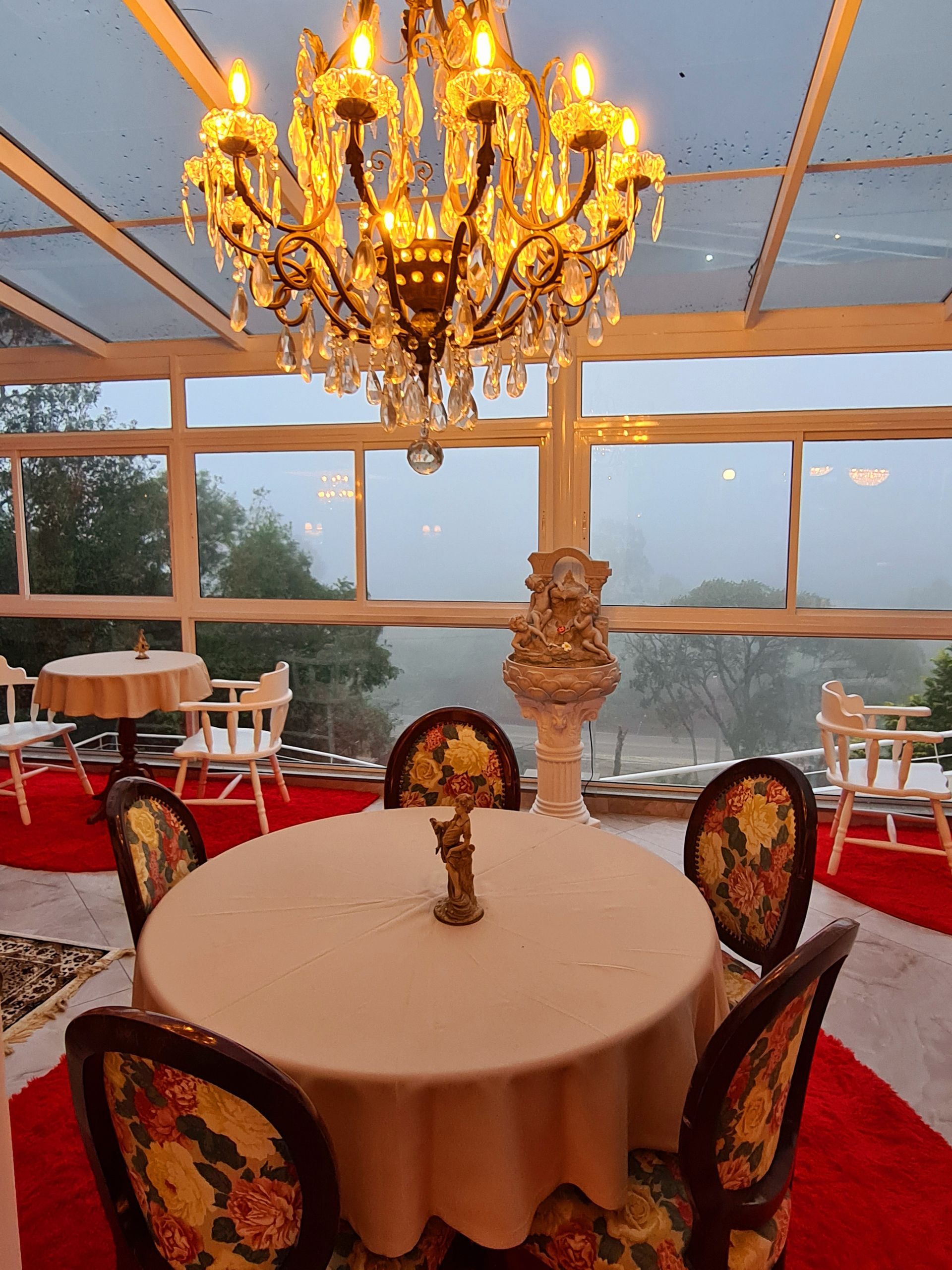 Uma sala de jantar com uma mesa redonda e cadeiras sob um lustre
