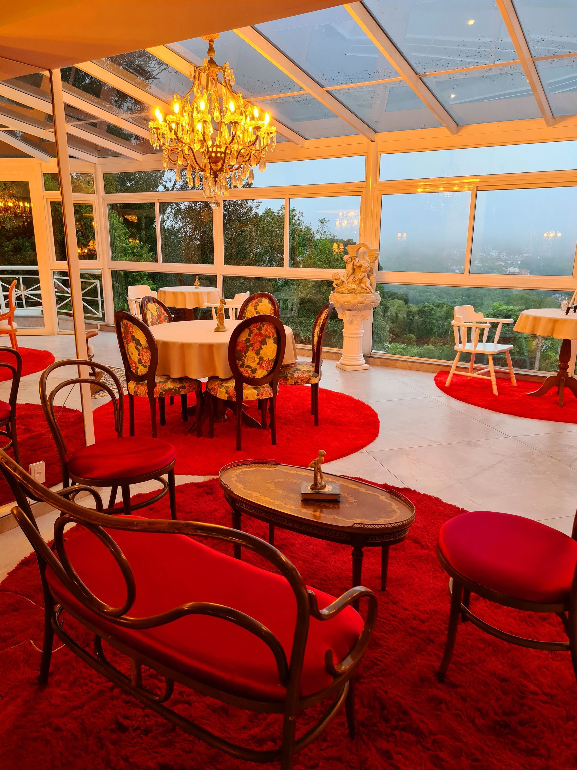 Uma sala de jantar com mesas e cadeiras e um lustre.