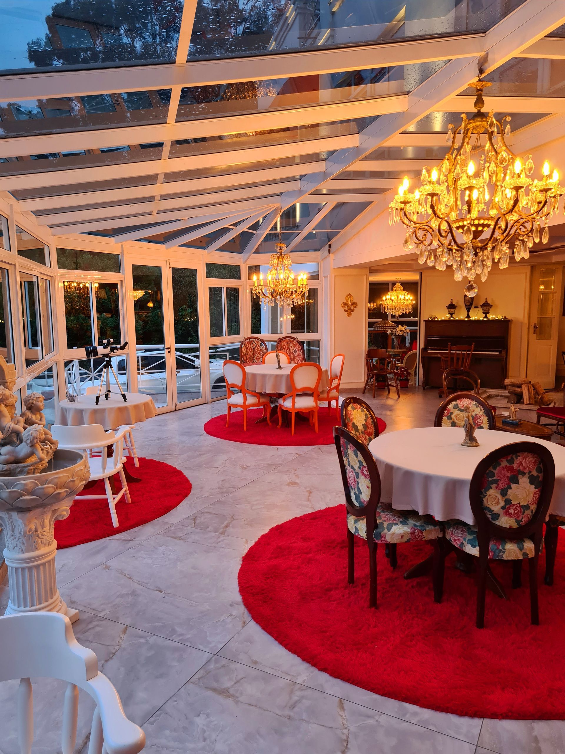 Uma sala grande com mesas e cadeiras e um lustre.