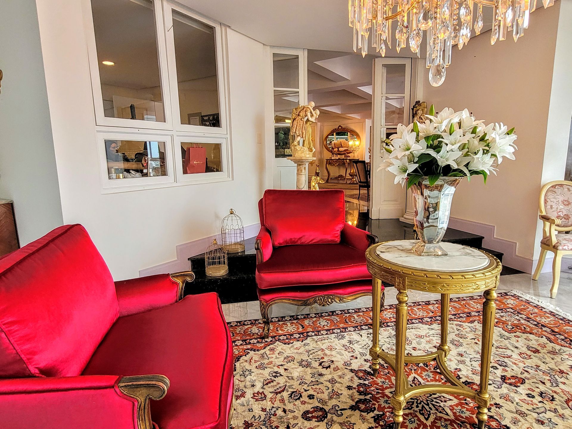 Uma sala de estar com cadeiras vermelhas, uma mesa e um vaso de flores.