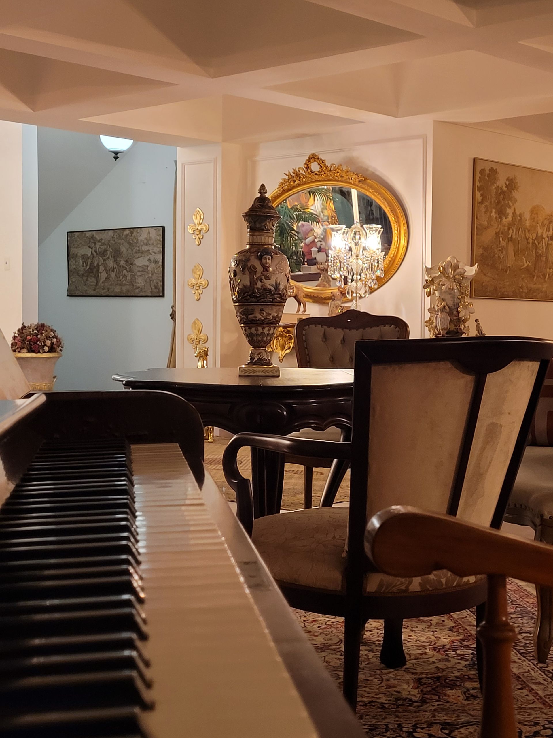 Um piano em uma sala de estar com cadeiras e uma mesa